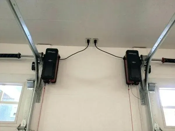 Two LiftMaster wall mount jackshaft openers installed side by side in a garage