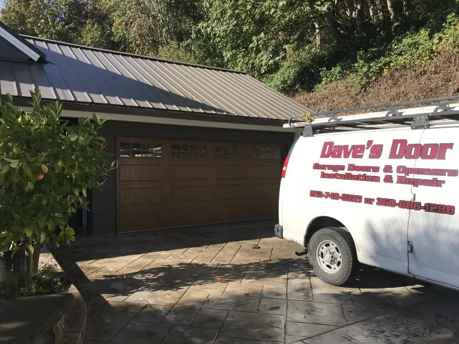 The Dave's Door van parked in front of a completed wood panel garage door installation