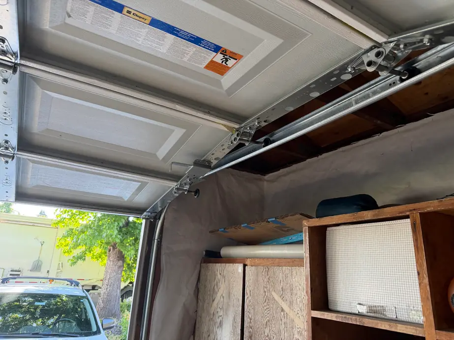 Looking up at the spring and track hardware above a garage door during a repair